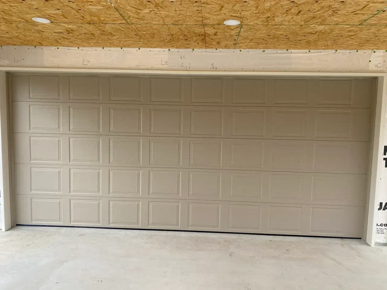Tan garage door with square panel design, indoors.