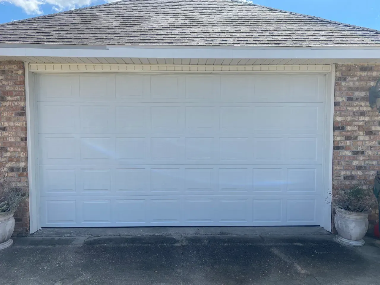 White garage door on a brick house under a blue sky.