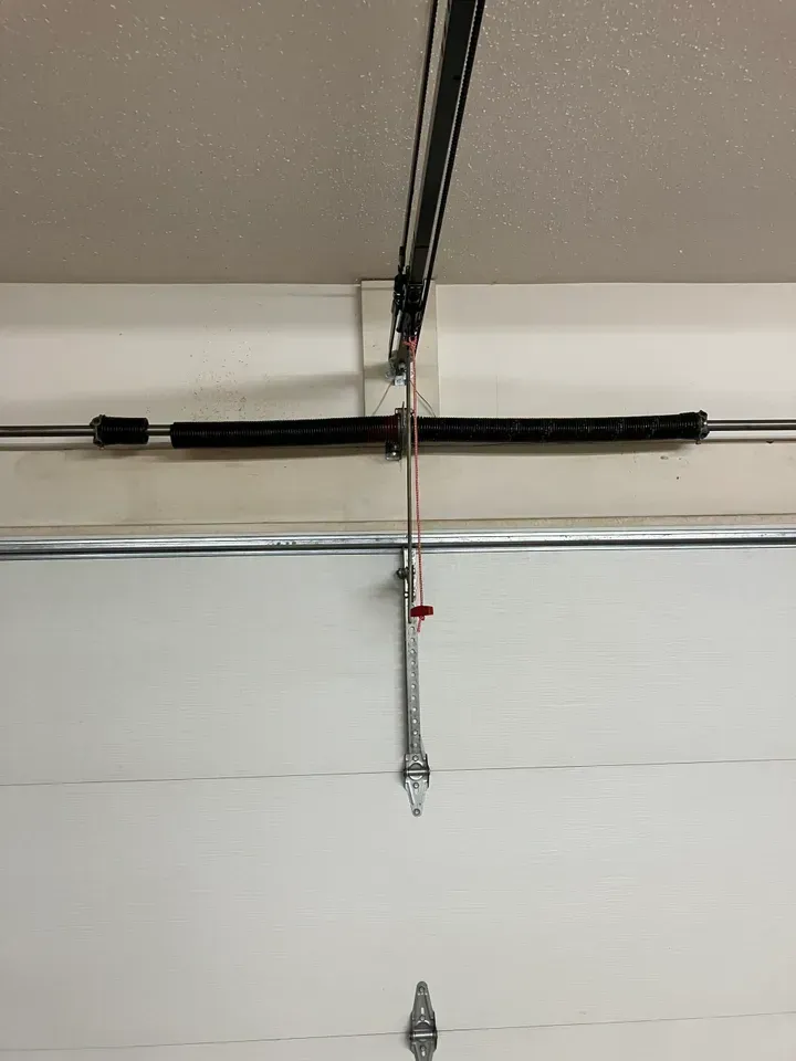 Garage door with a wrench hanging down, likely to disconnect opener from door.