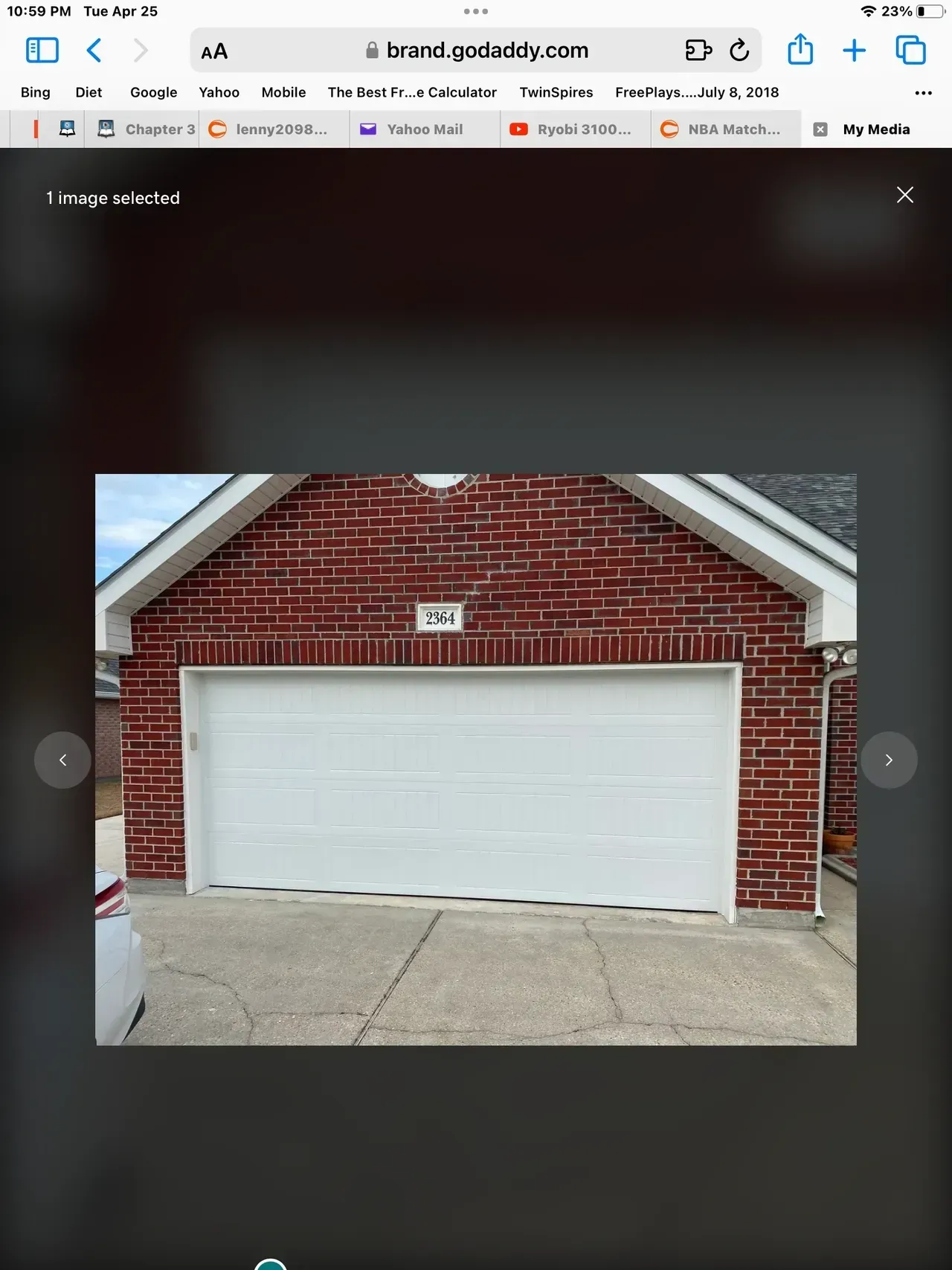 White garage door on a red brick building with a concrete driveway under a blue sky.