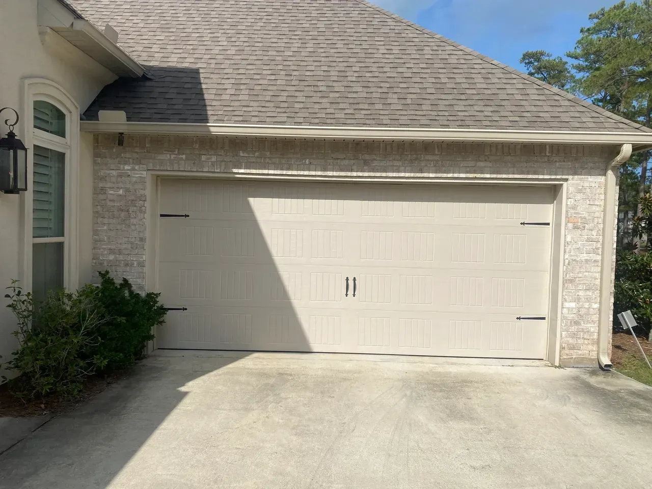 Garage door of a house with brick facade and light colored panels.