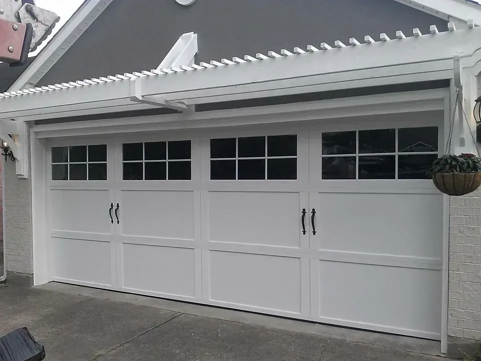 White garage door with windows, trellis, and hanging plant.