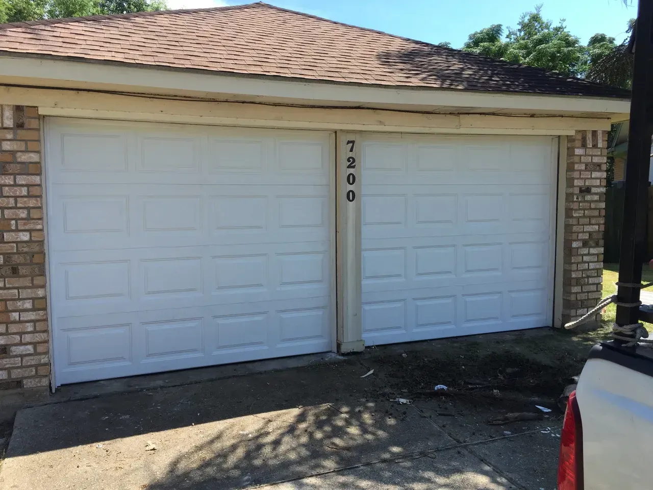 White garage doors on a brick building with the number 7200.