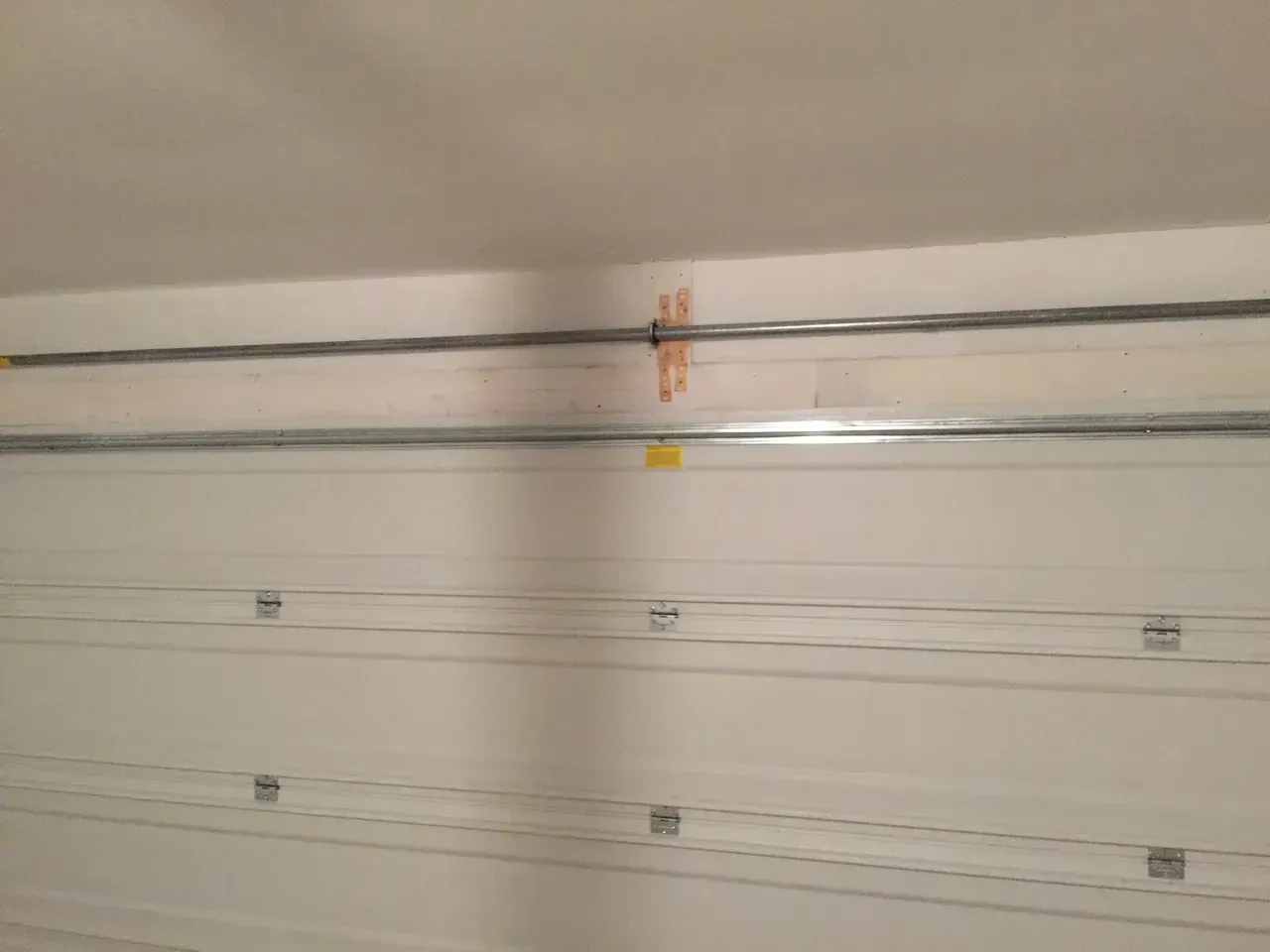 Inside of a garage, view of a garage door and overhead tracks.