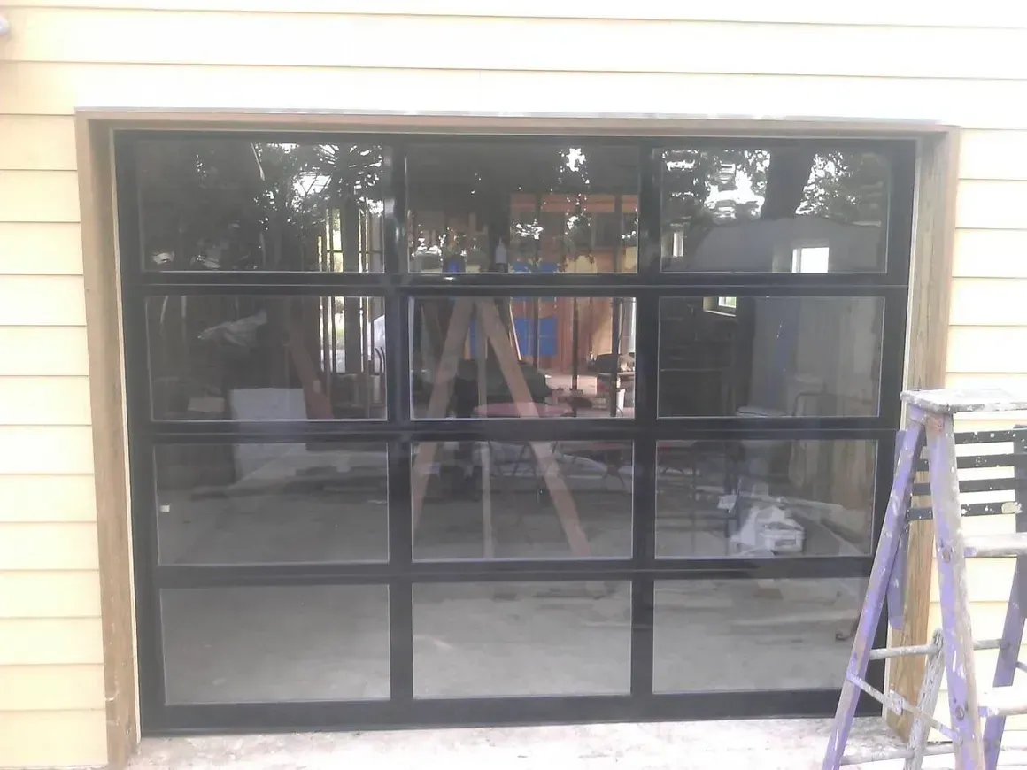 Glass garage door with black frame reflecting the surroundings.