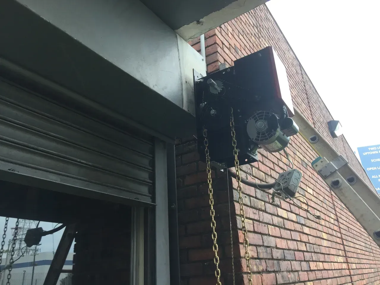 Motorized rolling shutter mechanism mounted on a brick building exterior.