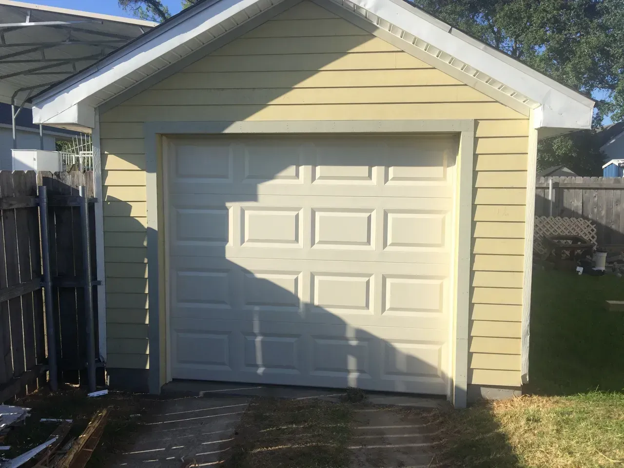 Yellow garage with a white panel door and driveway.