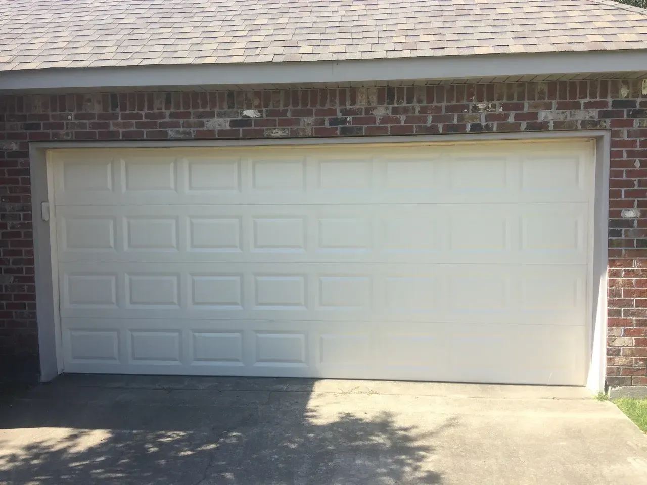 White garage door on brick building with a concrete driveway.