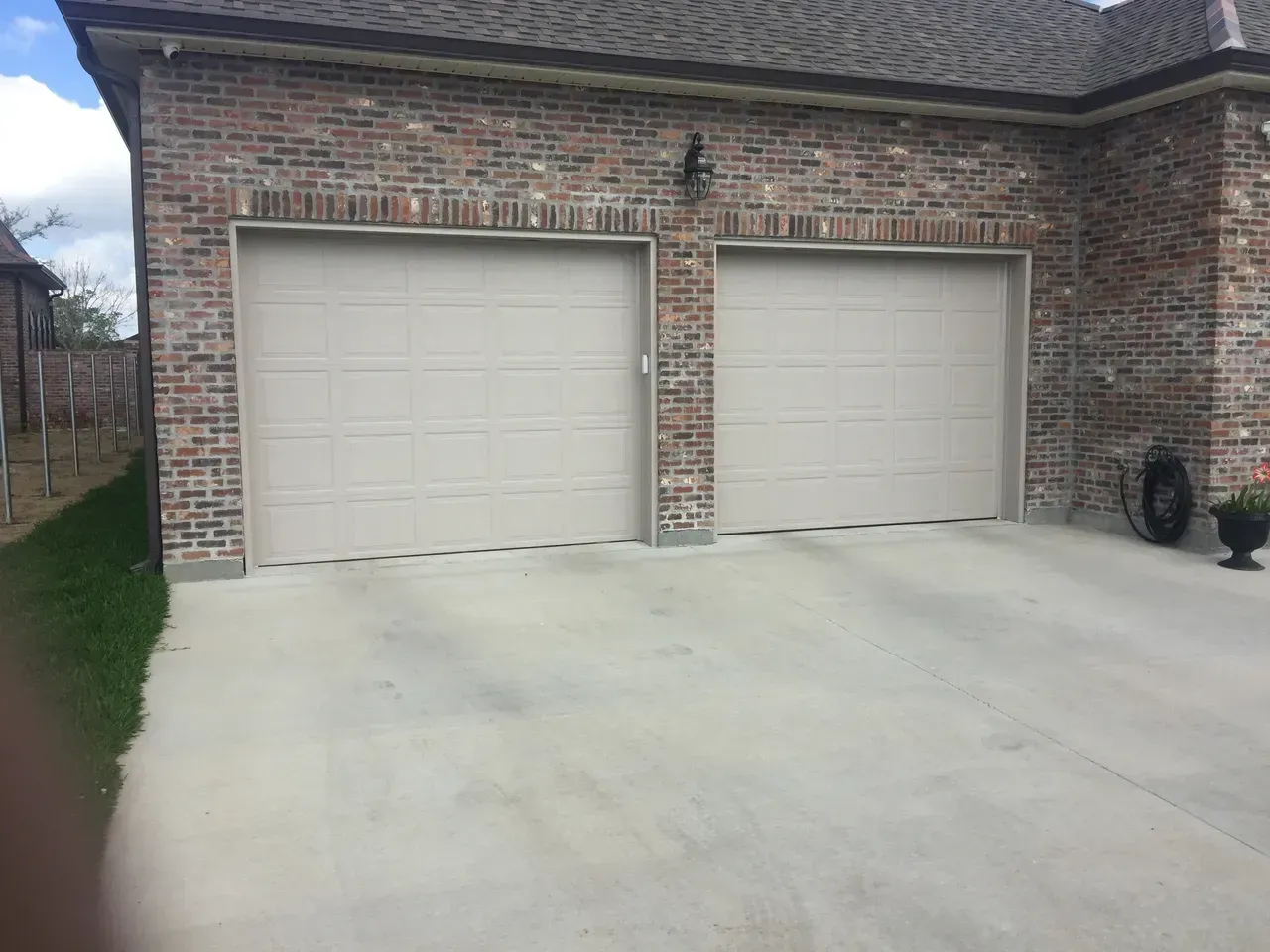 Double garage with beige doors and brick exterior. Concrete driveway.