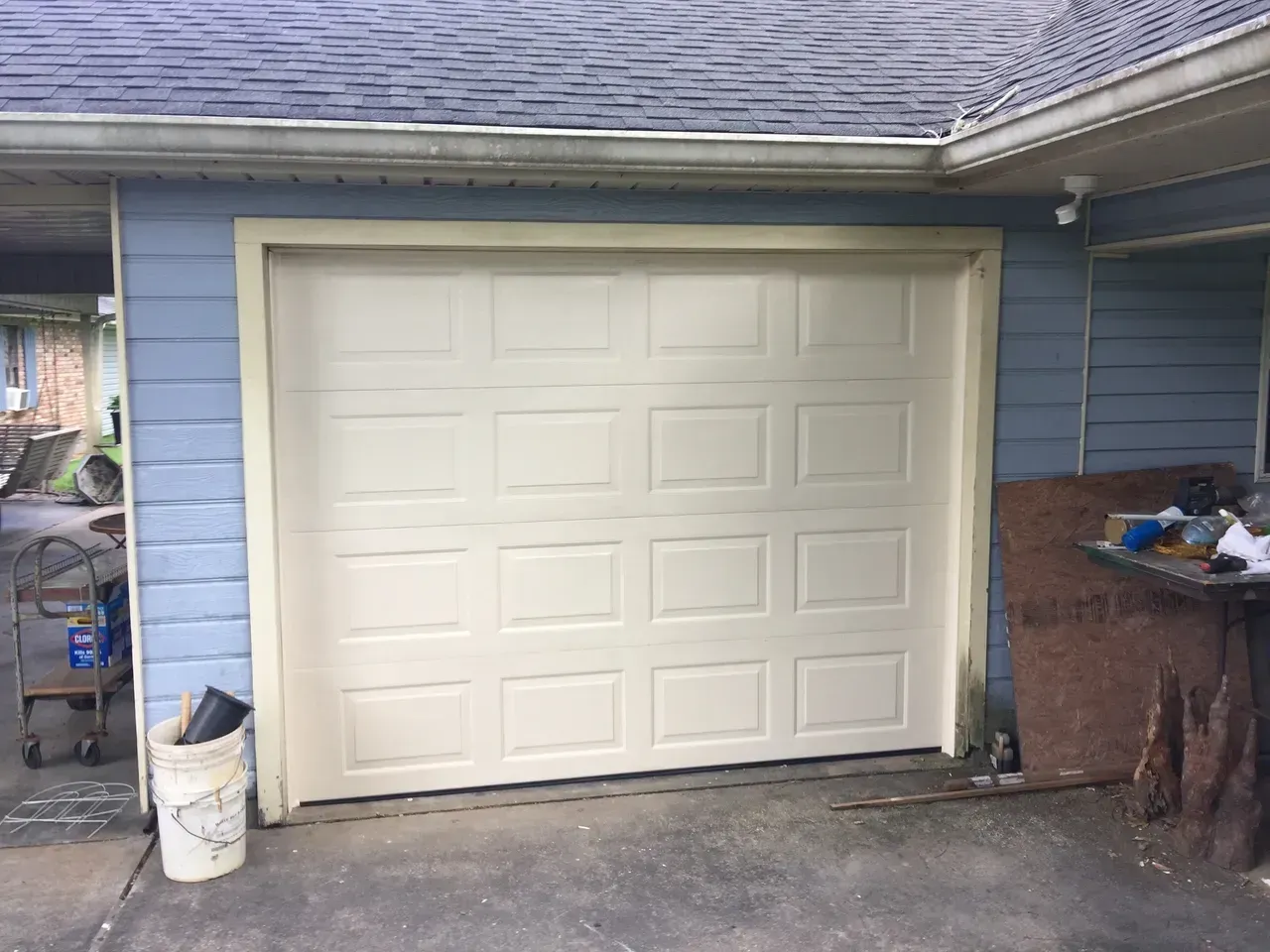 Cream-colored garage door set into a light blue building with tan trim.