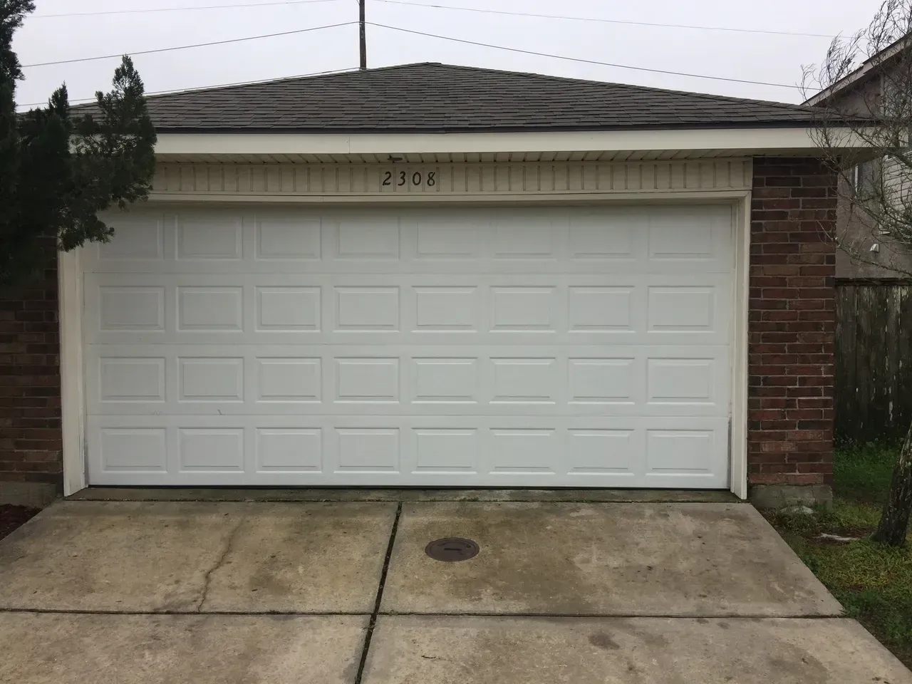 White garage door with brick and concrete exterior, number 2386 above the door.
