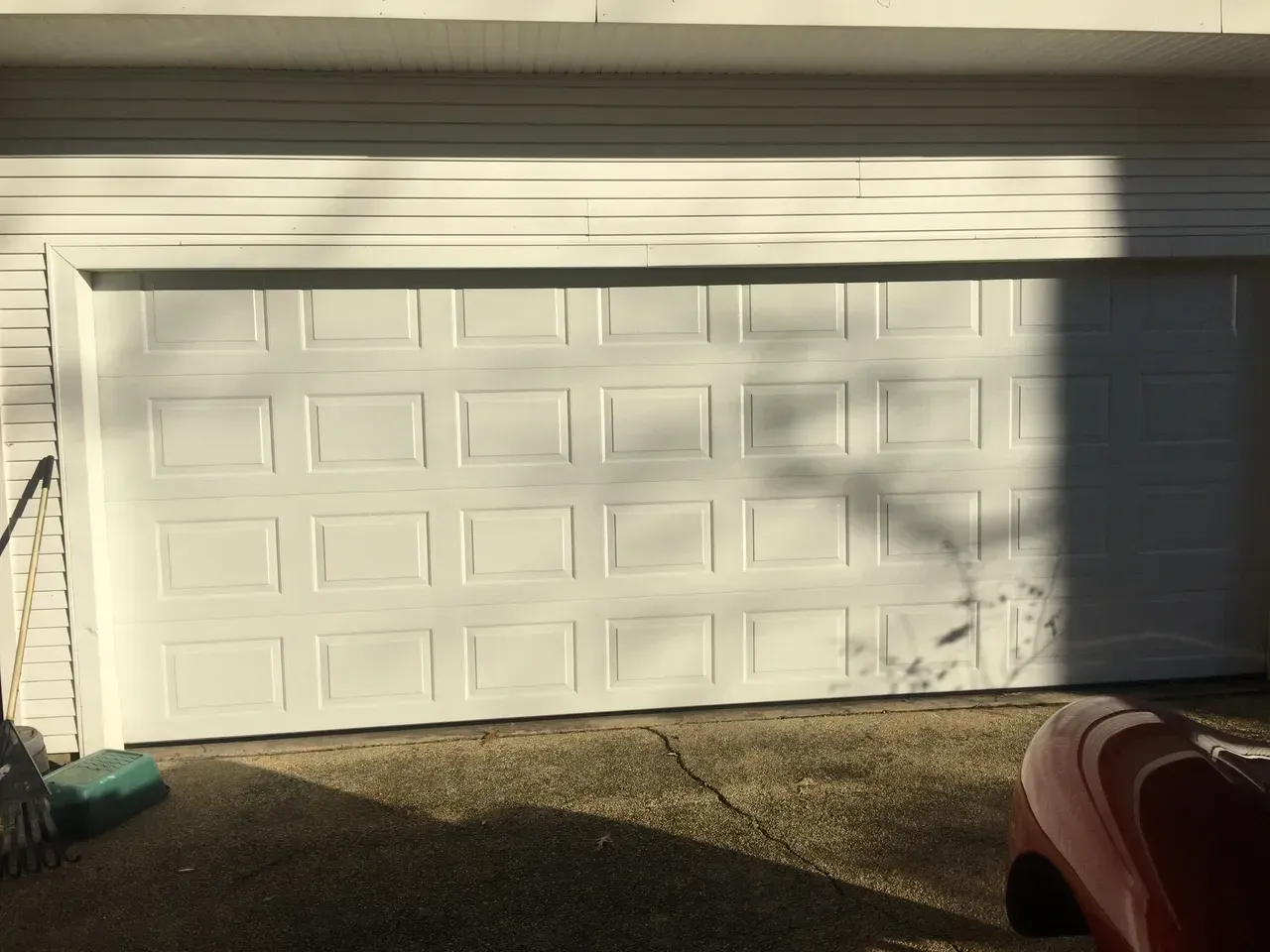 White garage door, exterior, with sunlight casting shadows.
