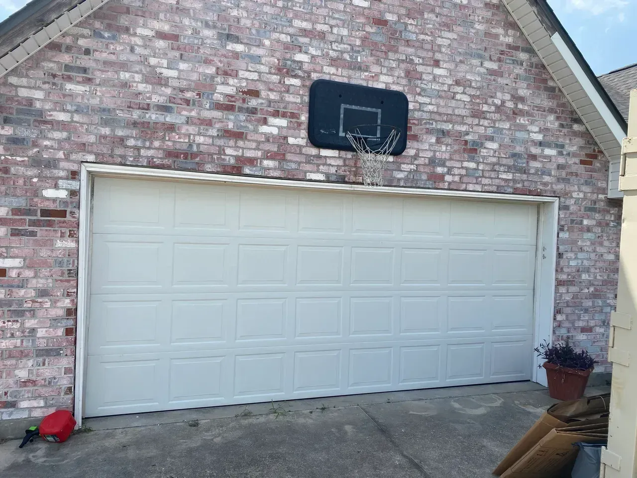 Garage with basketball hoop on brick wall. Beige garage door.
