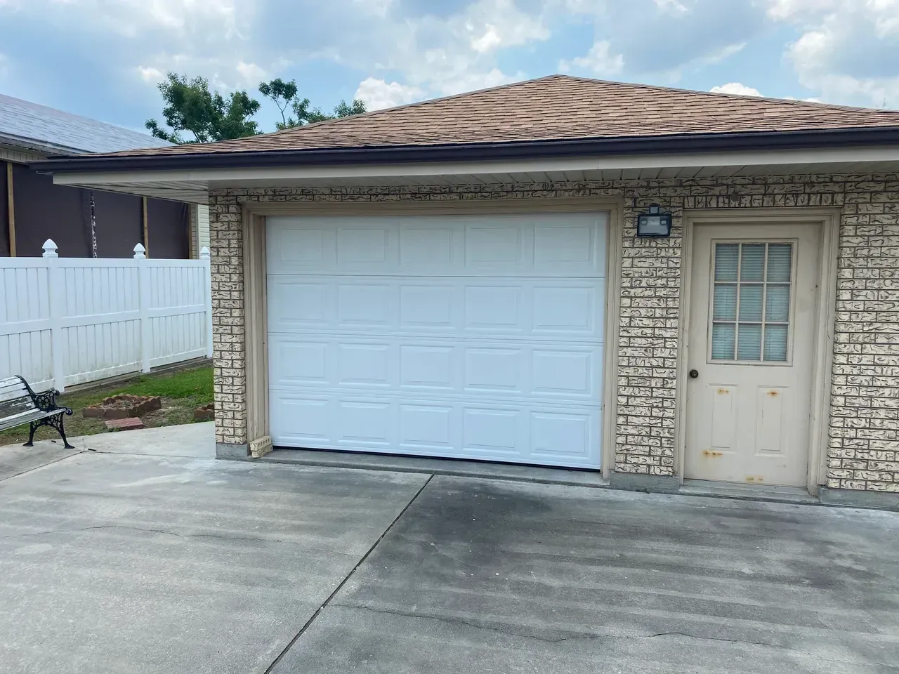 Garage with white door and weathered, tan brick exterior, and a small door.
