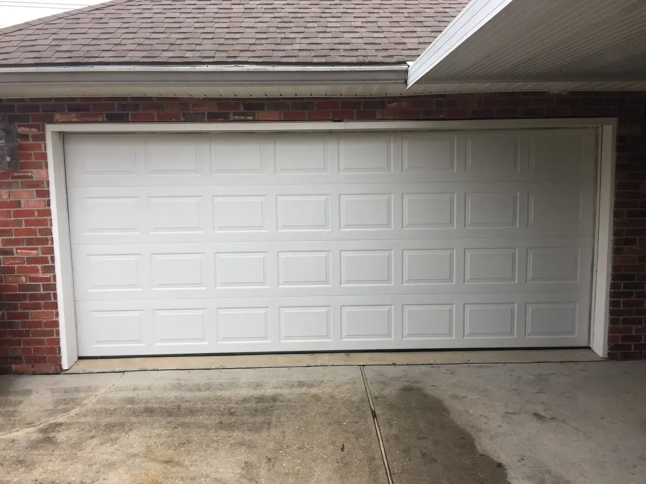 White garage door on a brick building with a concrete driveway.