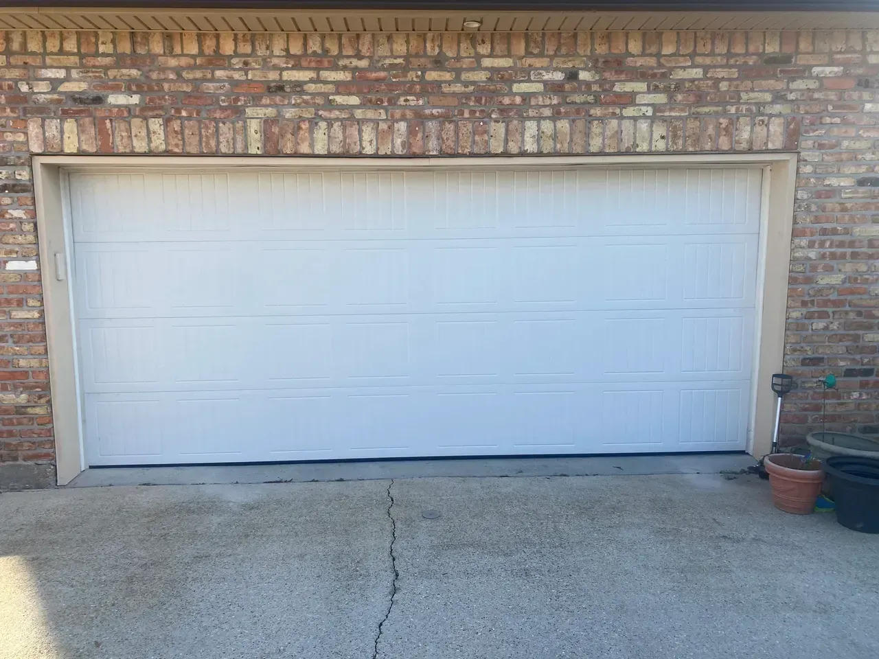 White garage door set in a brick building. Concrete driveway in front.