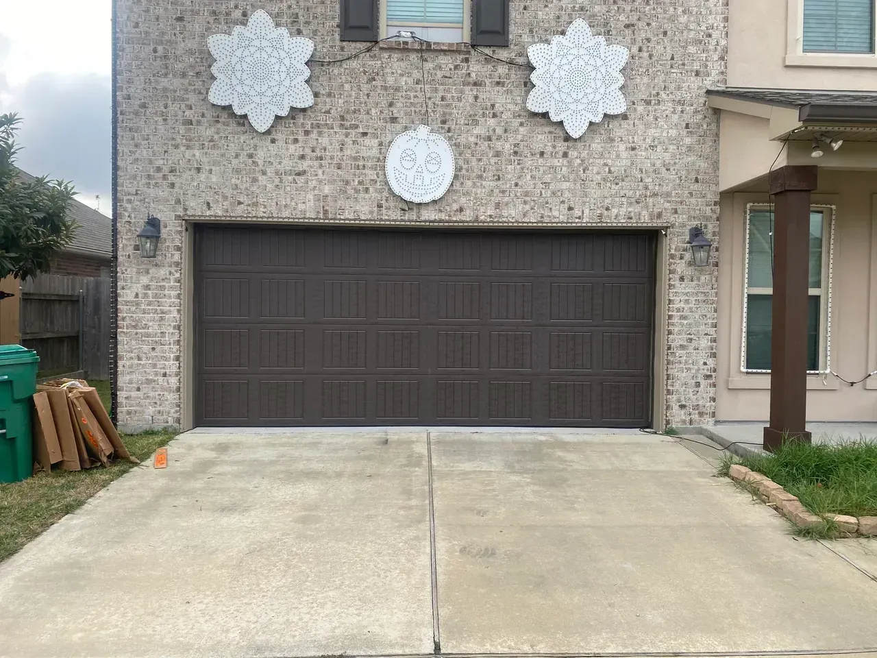 Brown garage door on brick house with decorative snowflake accents. Concrete driveway.