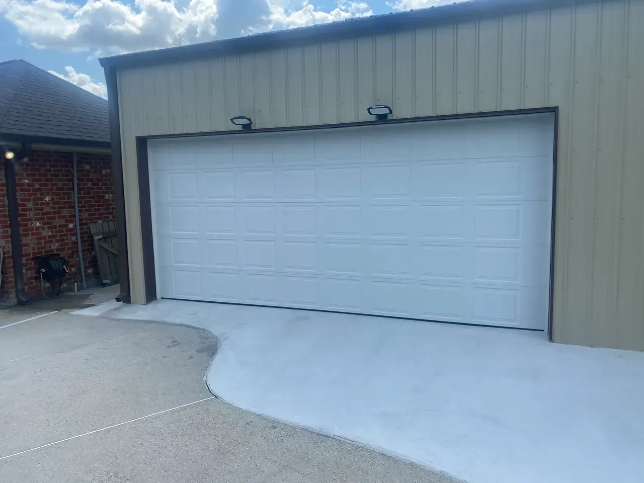 White garage door on a beige building with a concrete driveway.