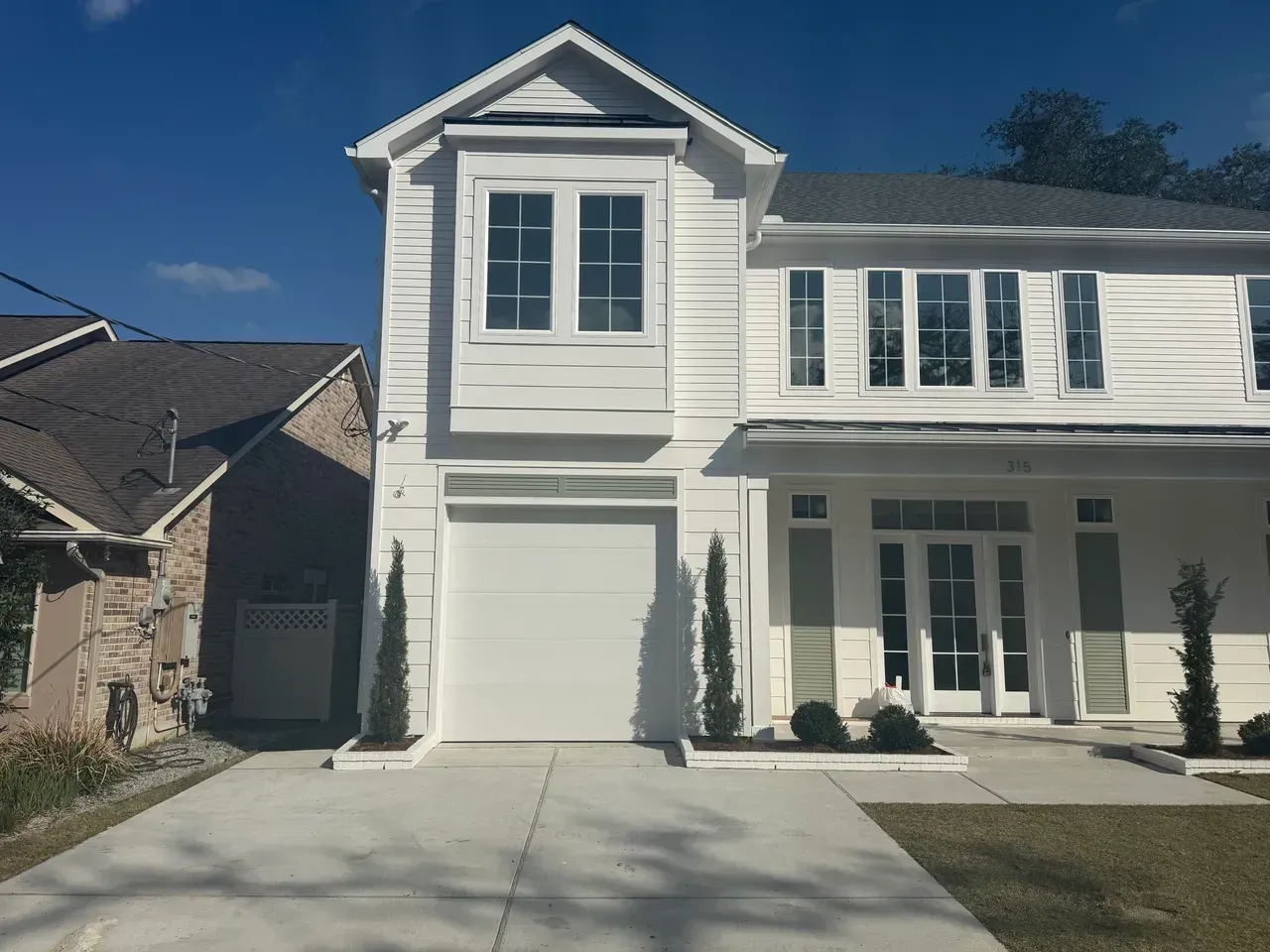 White two-story house with a garage and light-colored driveway against a blue sky.
