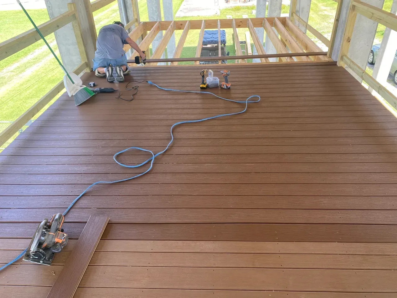 Man installing wooden deck boards with tools on an elevated platform.