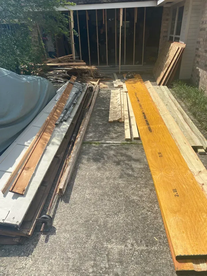 Exterior view of house under construction with wood planks on ground.