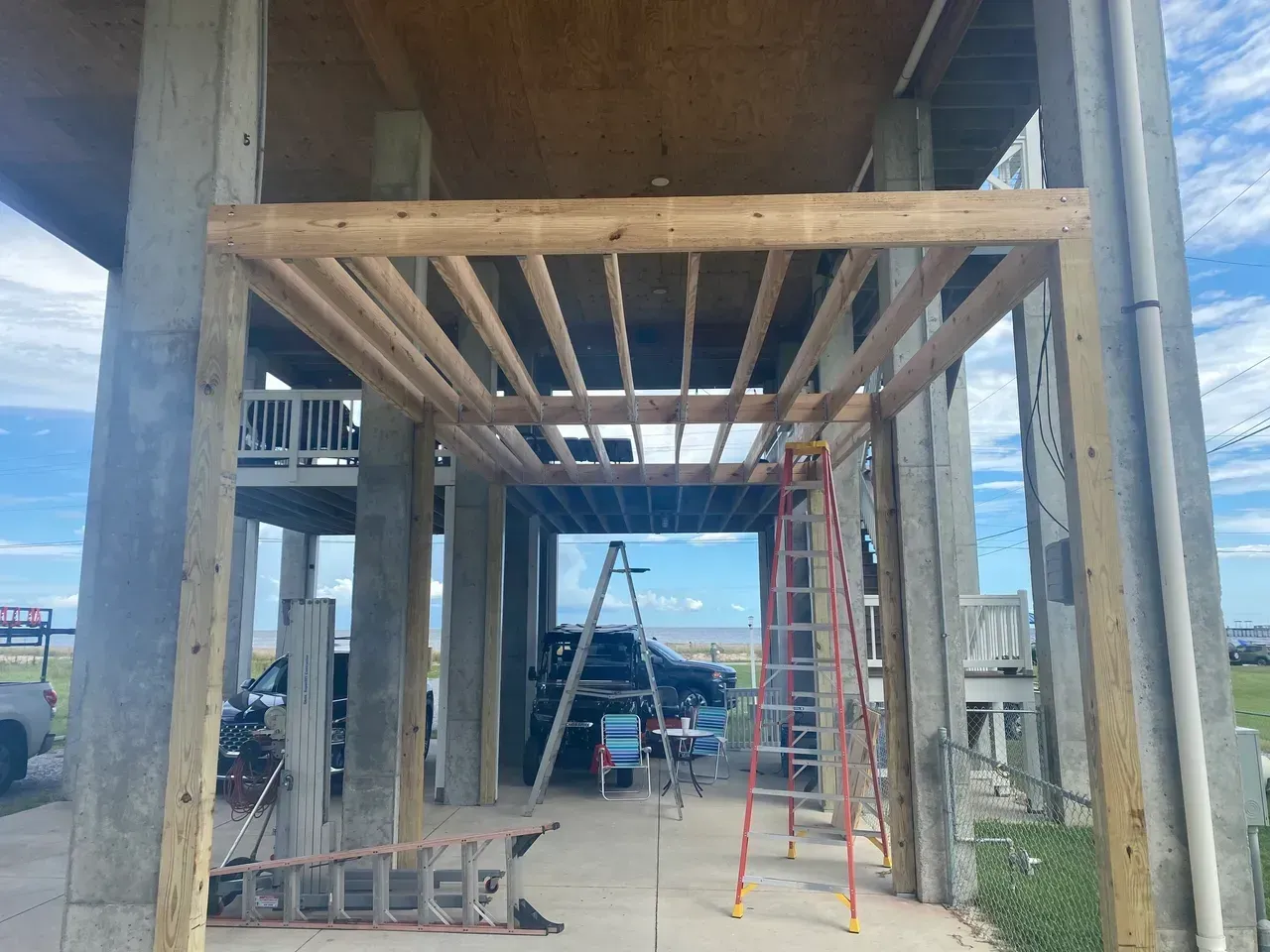 Coastal home under construction with wooden beams and a ladder.