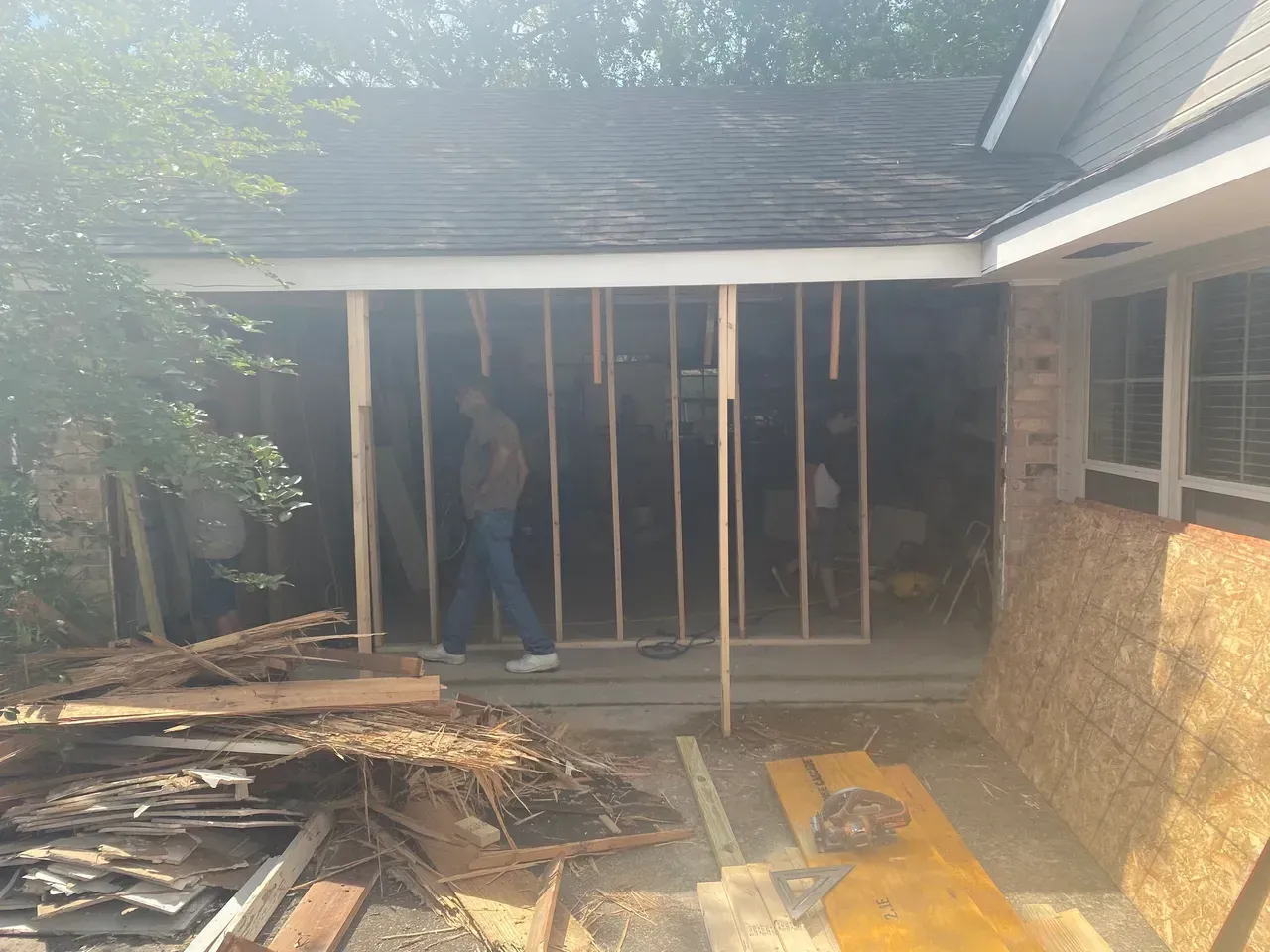 Construction of an exterior wall underway; person stands within the partially framed structure.