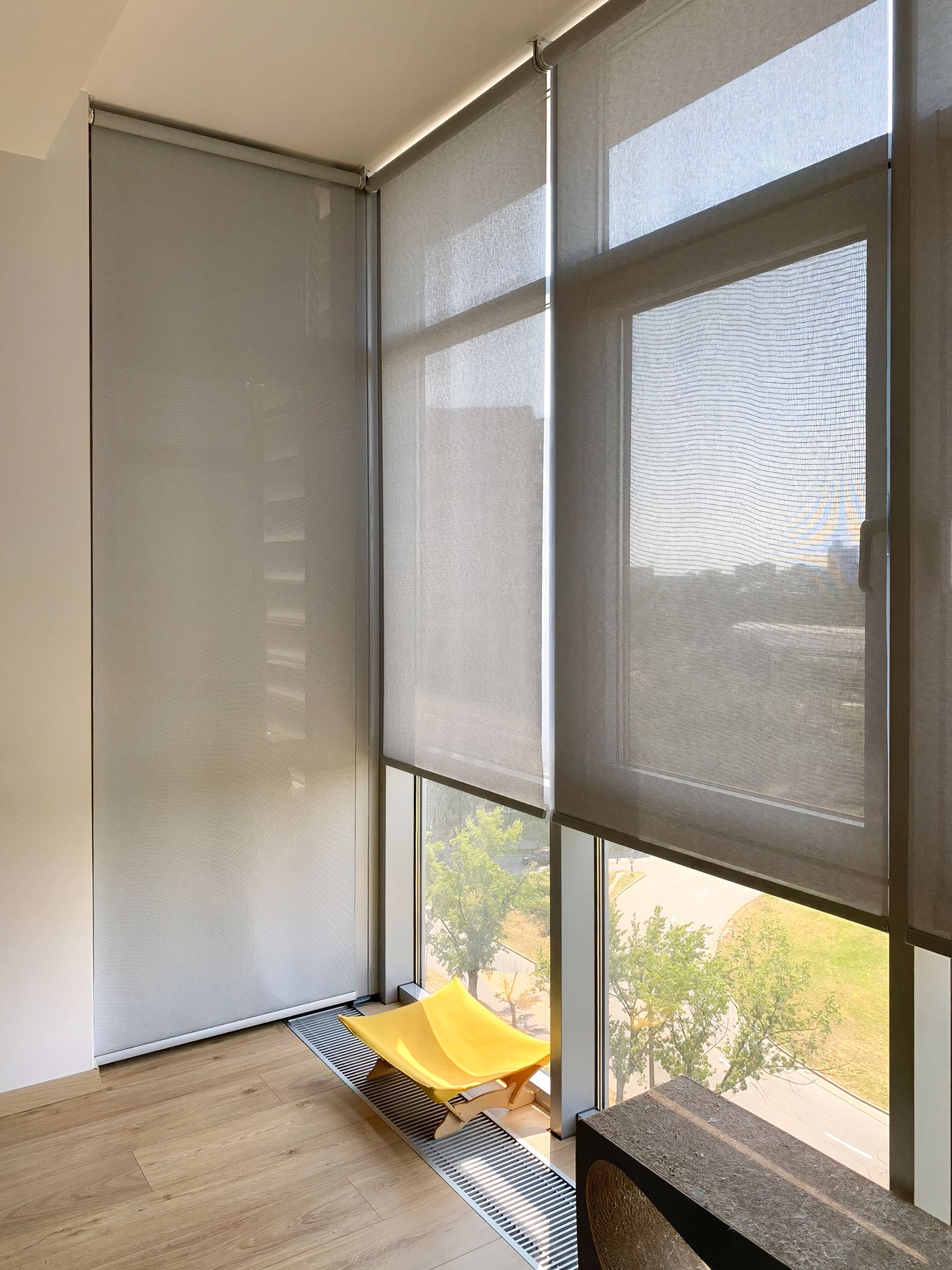 A room with a yellow chair and a large window with blinds.