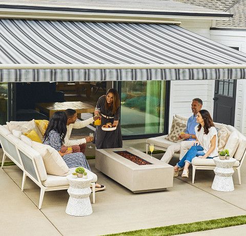 A group of people are sitting under an awning on a patio.