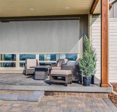 A patio with a table , chairs , and a fire pit.