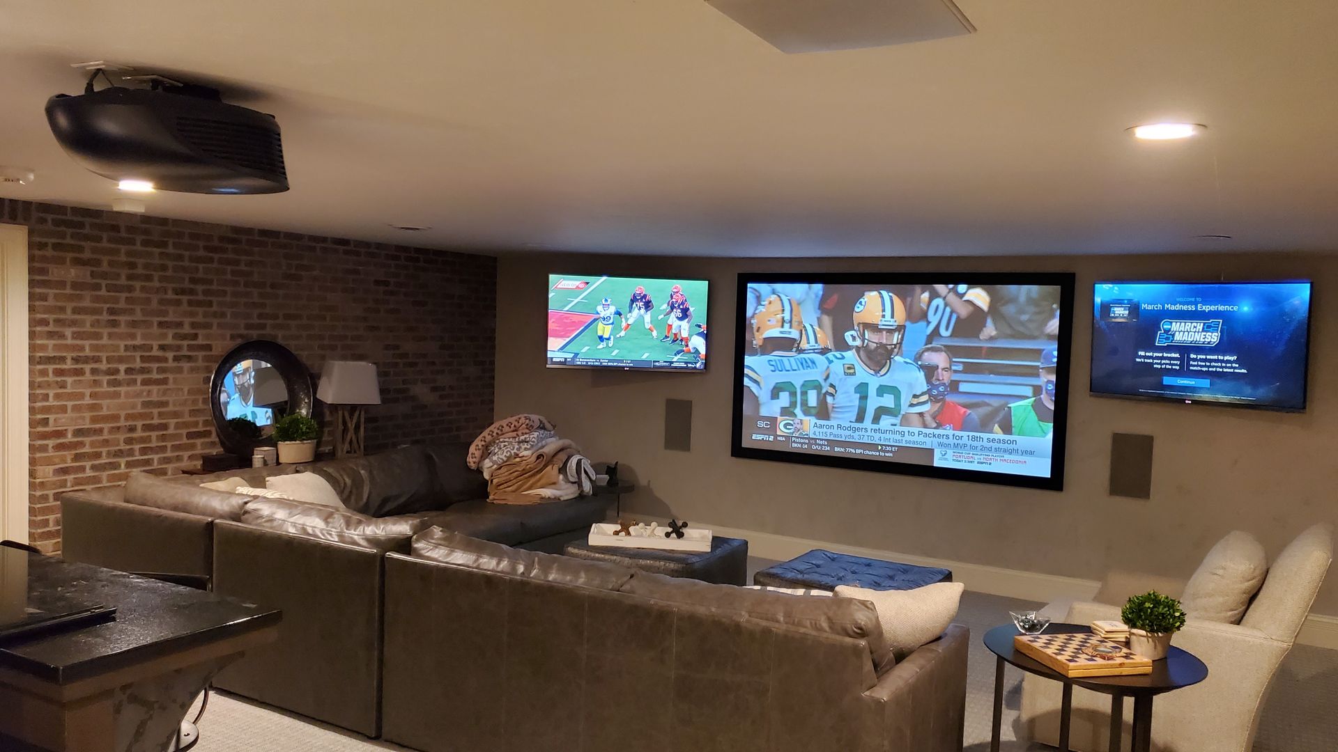 A living room with a couch and three televisions on the wall.
