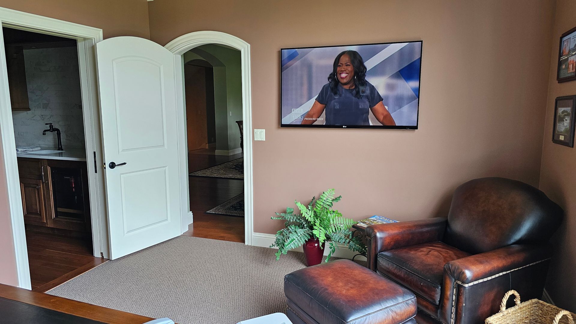 A living room with two chairs and a television on the wall.