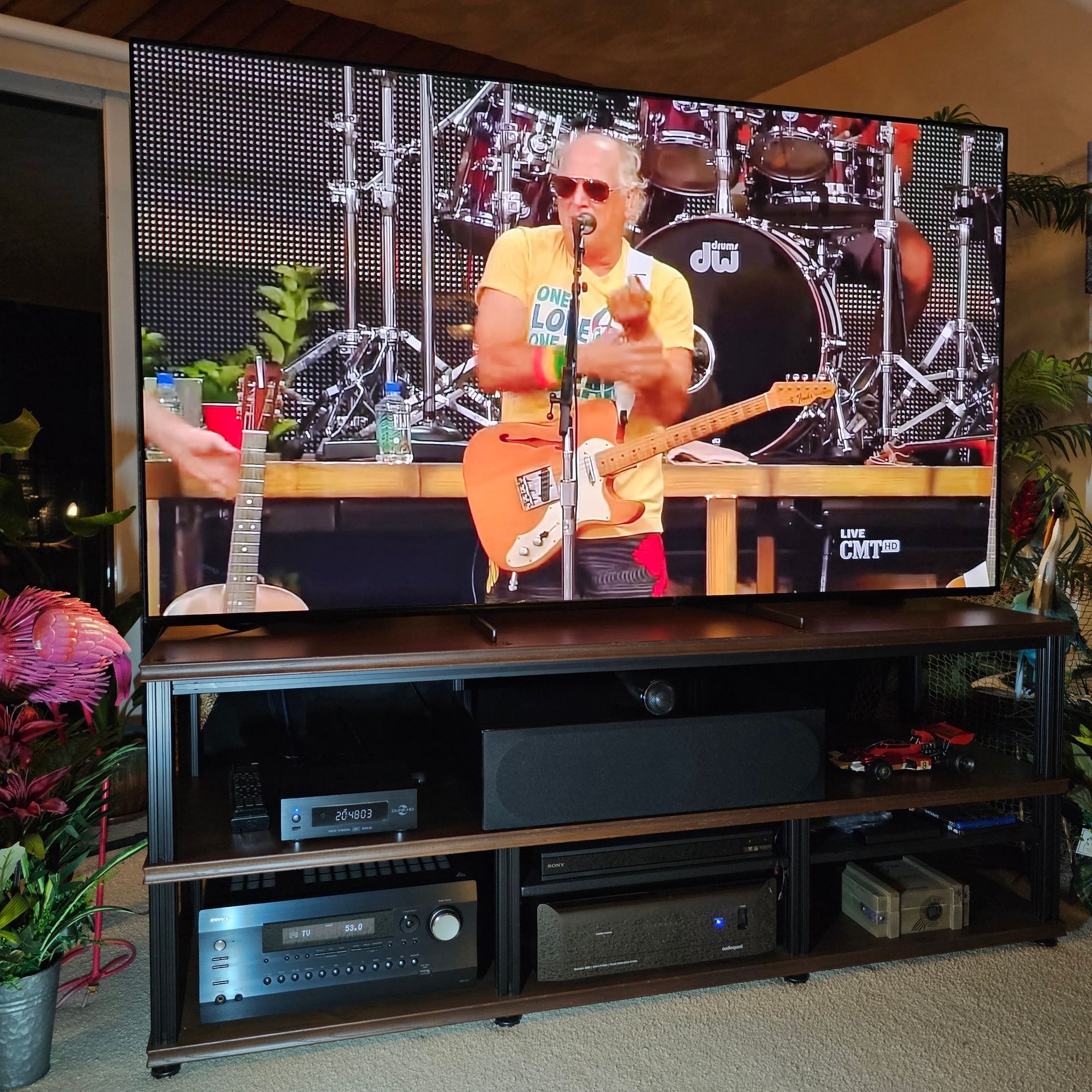 A large flat screen tv shows a man playing a guitar and singing into a microphone