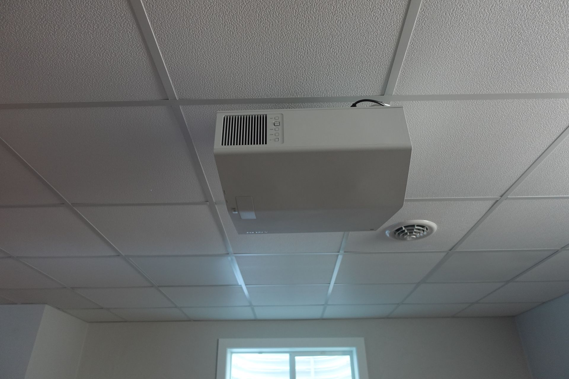 A white box is hanging from the ceiling of a room.