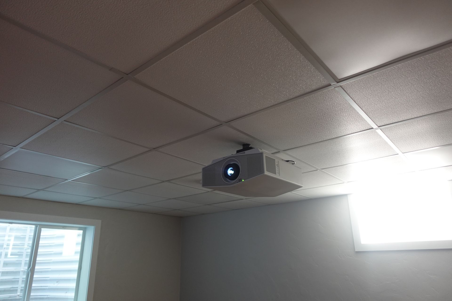 A projector is hanging from the ceiling of a room.