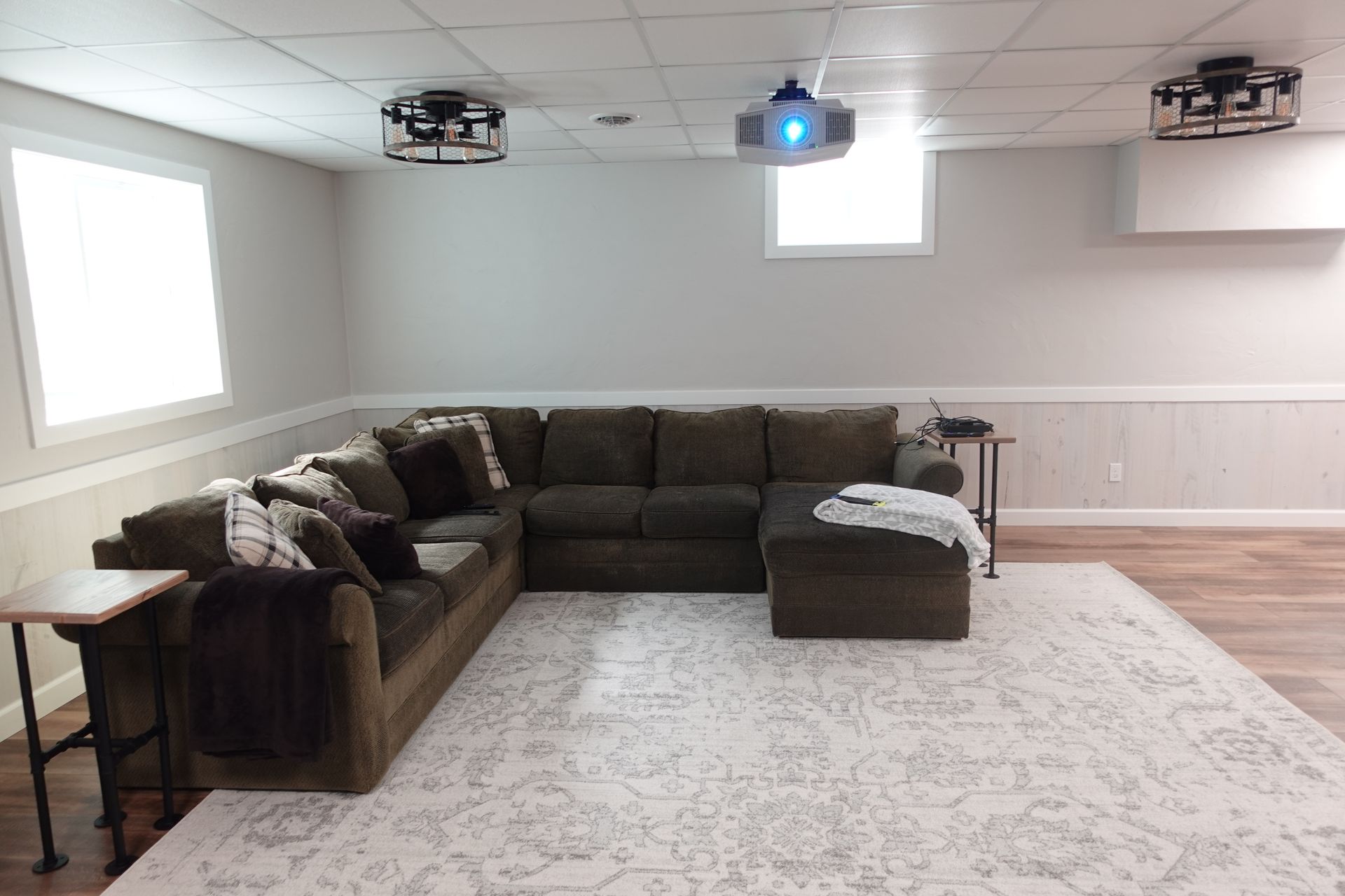 A living room with a sectional couch and a projector screen.