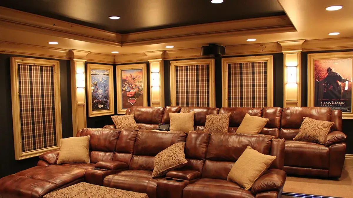 A home theater with a lot of leather couches and pillows.
