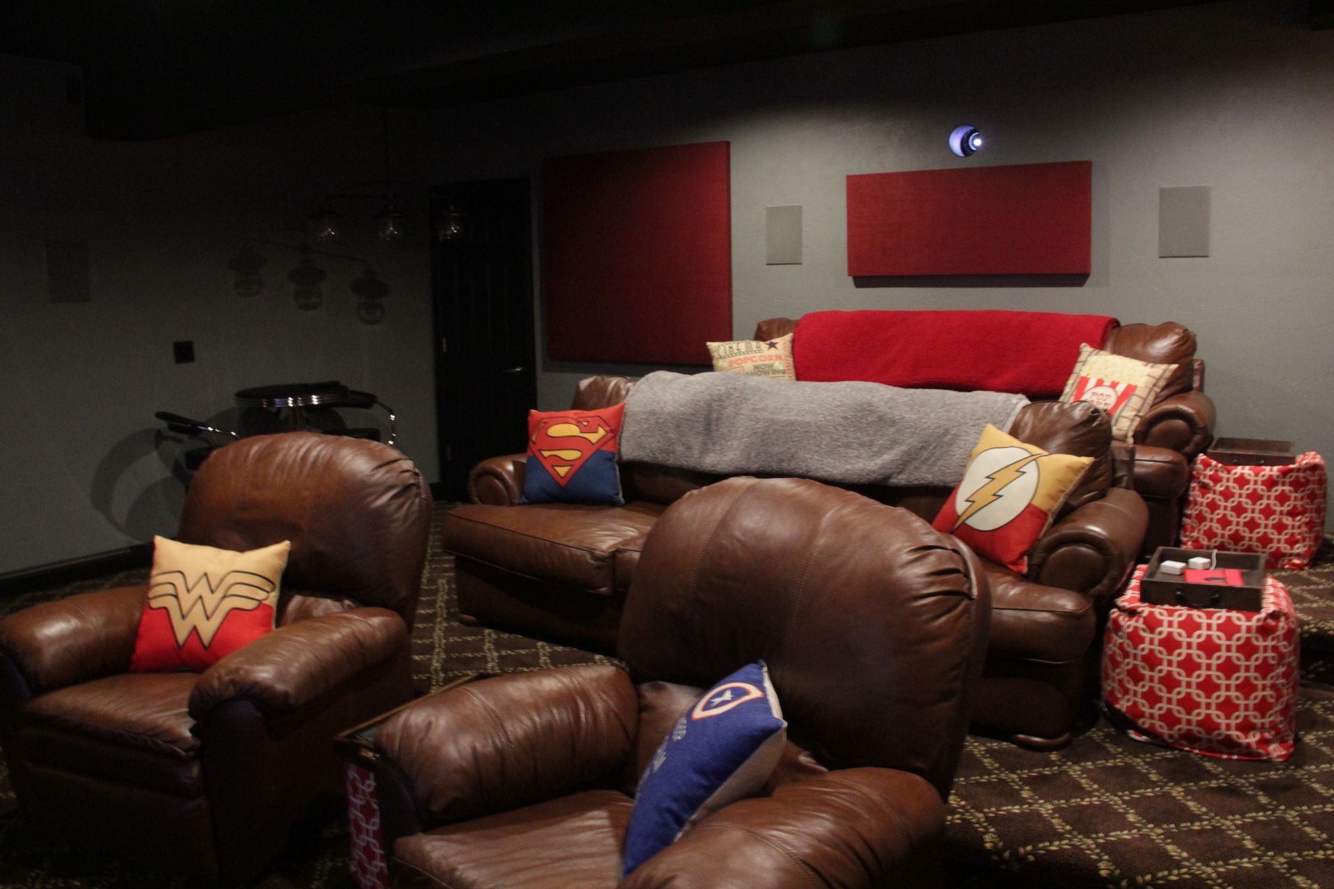 A movie theater with a couch and chairs with wonder woman pillows on them