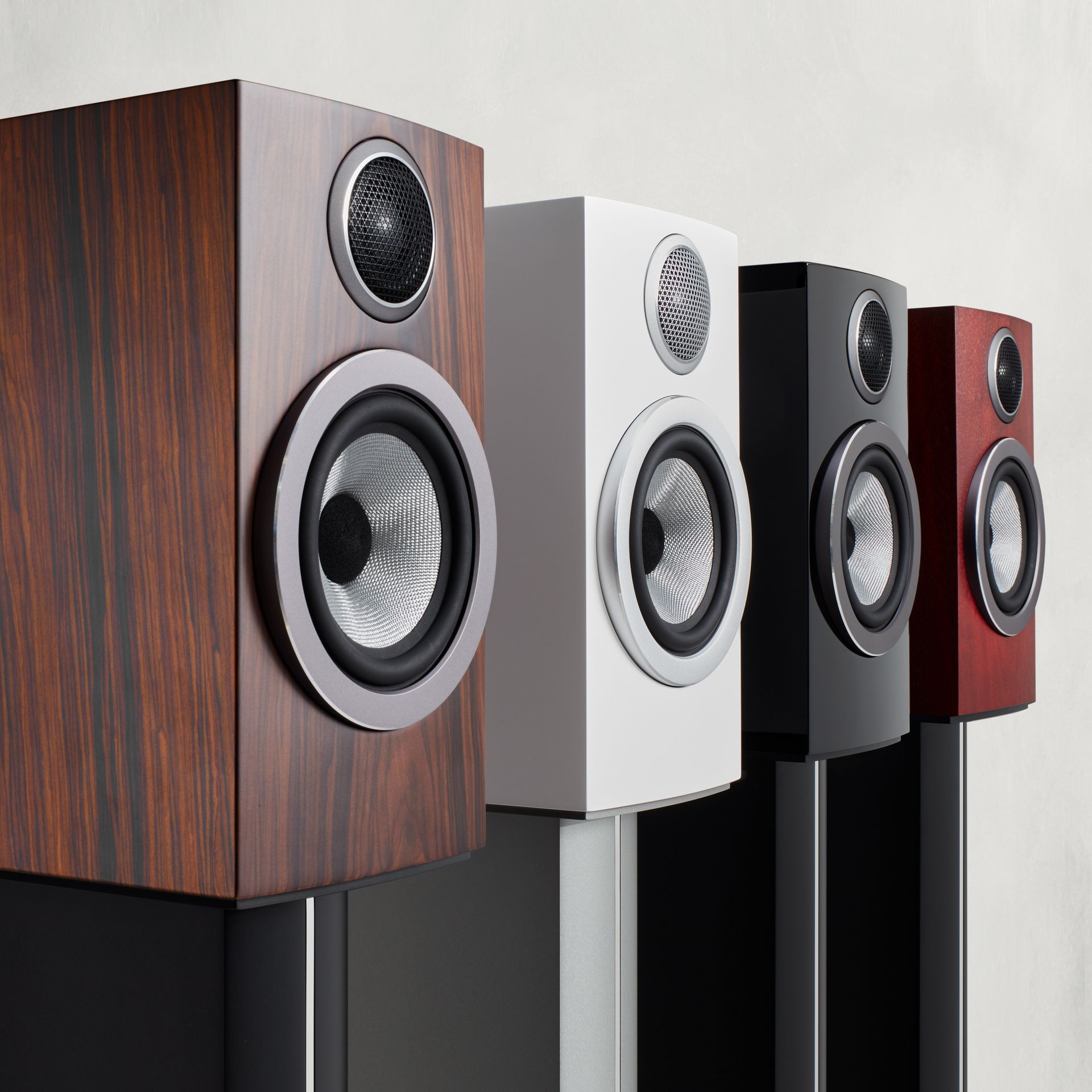 Four speakers are lined up in a row in different colors.