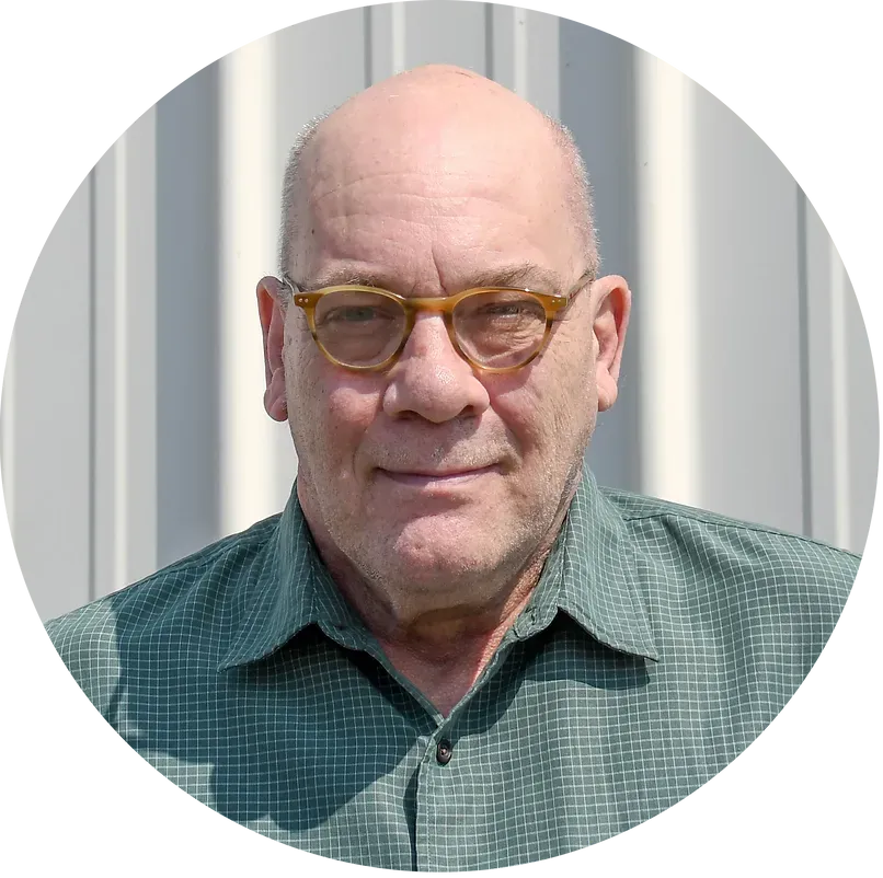 A bald man wearing glasses and a green shirt is in a circle.