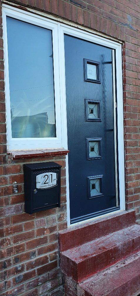 A black door with a window and a mailbox on the side