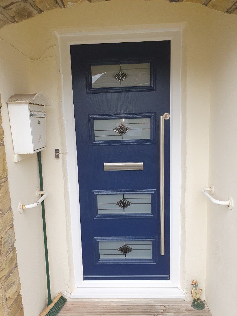 A blue door with a stainless steel handle is sitting in a porch