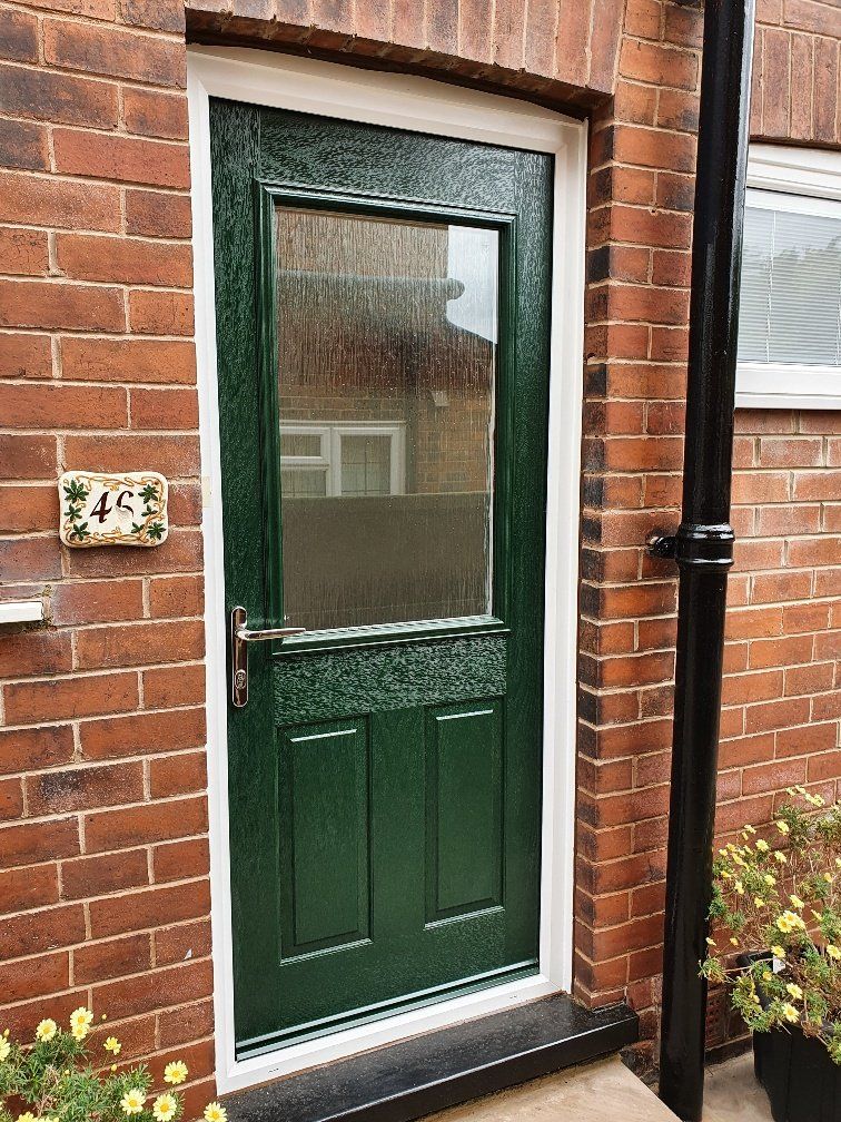 A green door is on a brick wall 