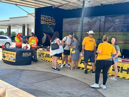 A group of people are standing around a table at a road show.