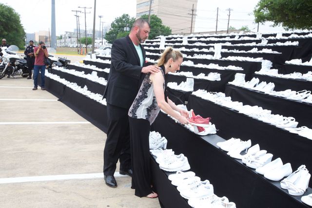 A man and a woman are looking at a display of white shoes