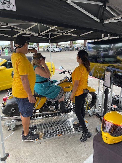 A woman is sitting on a yellow motorcycle in a parking lot