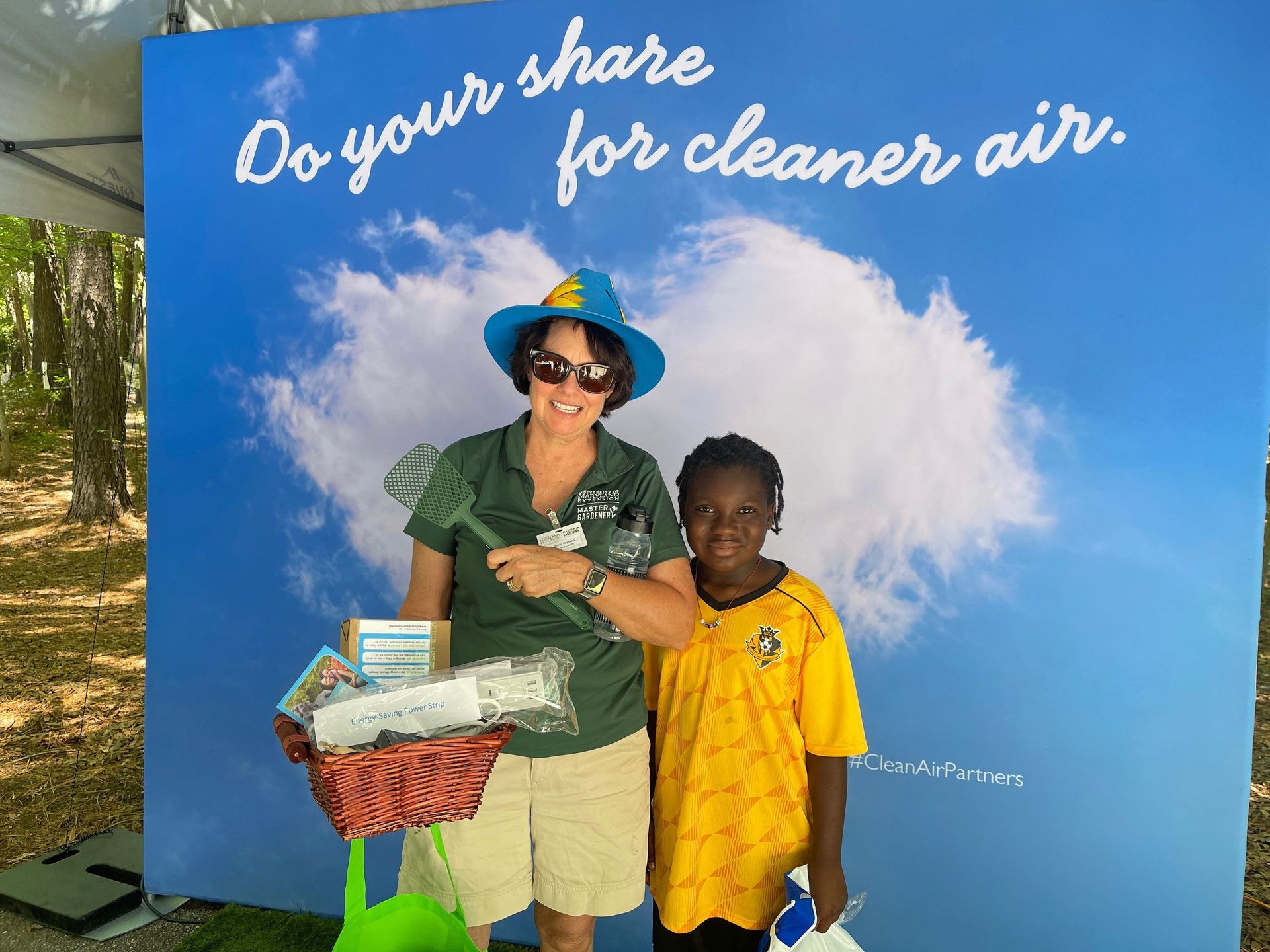 A woman and child pose in front of a sign that says do your share for cleaner air