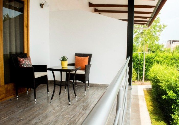 Balcón con muebles negros, planta en maceta y vista a una exuberante vegetación.