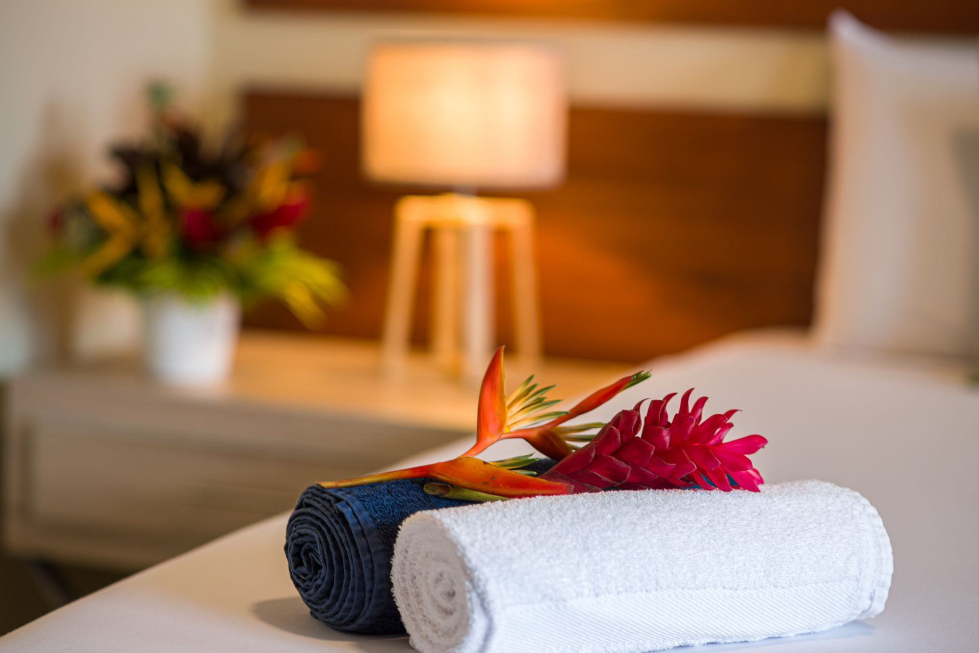 Toallas enrolladas con flores sobre una cama en una habitación de hotel.