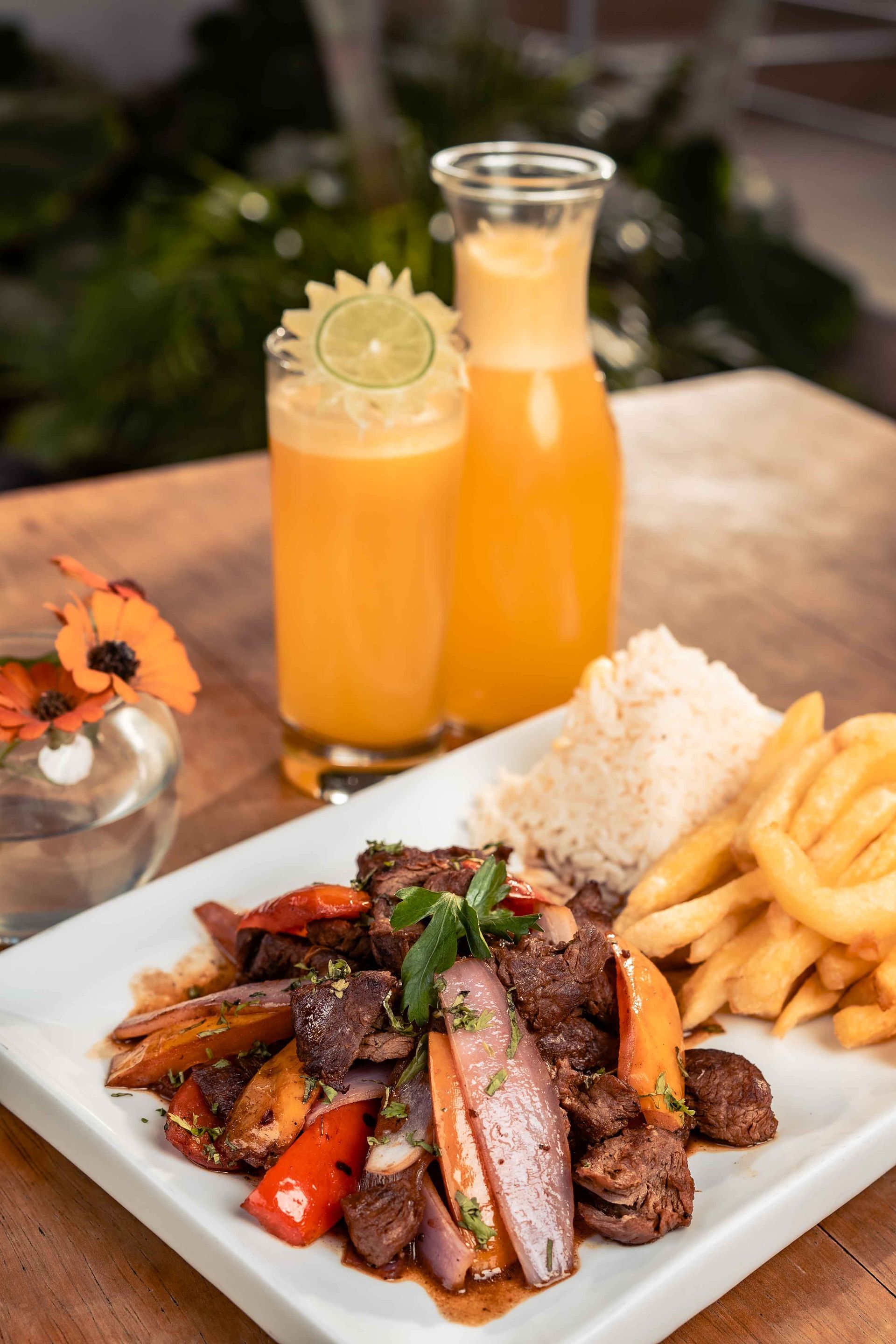 Bistec con arroz, papas fritas y jugo de naranja en una mesa.